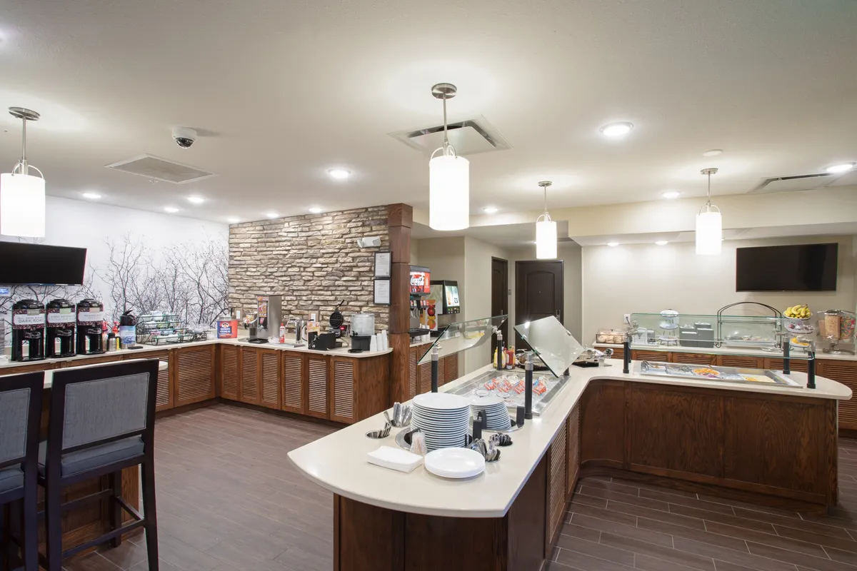 A spacious breakfast area with a well-stocked buffet, a dedicated coffee station, and a variety of seating options. Guests are seen enjoying breakfast and socializing, creating a lively and friendly atmosphere perfect for both families and business travelers.