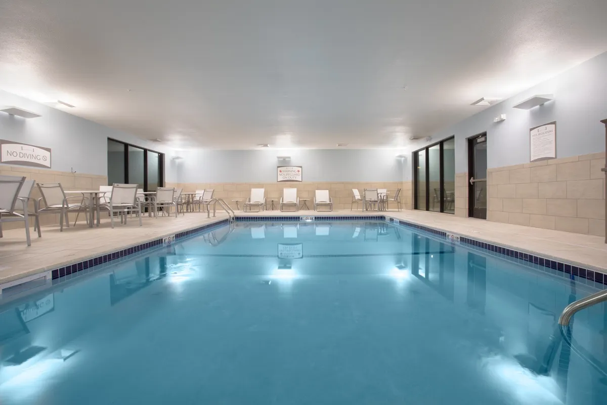 A tranquil indoor pool area with clear water, inviting lounge chairs, and subtle signage. The peaceful atmosphere encourages relaxation, swimming, and poolside socializing, making it a welcoming space for guests to recharge and connect.